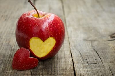 A red apple with a heart-shaped bite taken out of it.